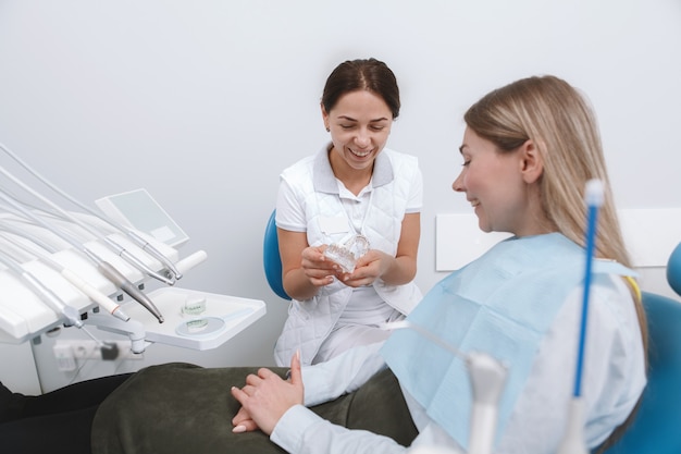 Dentista femminile parlando al suo paziente, sorridendo allegramente