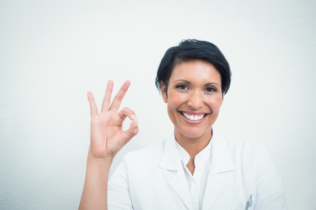 Dentista femminile sorridente che gesturing segno giusto