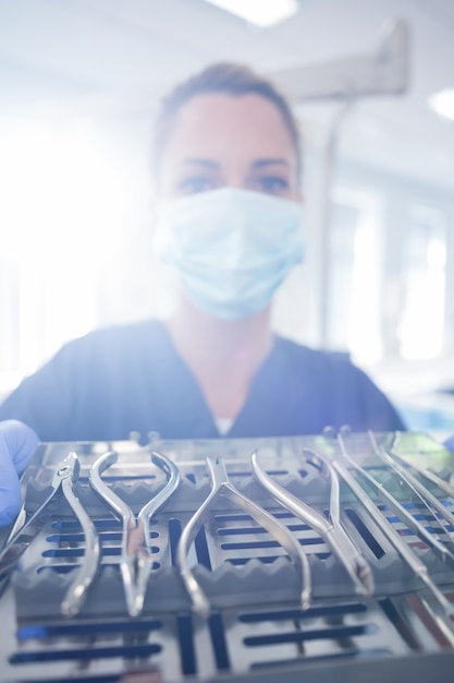 Dentista in blu scrub mostrando vassoio di strumenti