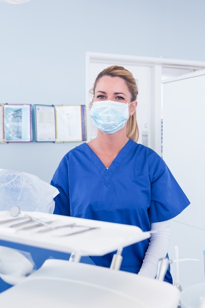 Dentista in maschera dietro il vassoio di strumenti presso la clinica odontoiatrica