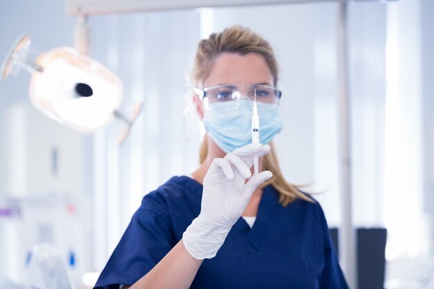 Dentista in maschera e guanto in possesso di un&#39;iniezione