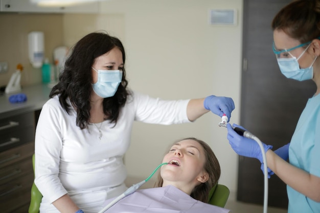 Dentista in un ufficio dentistico che parla con una paziente femminile e si prepara per il trattamento