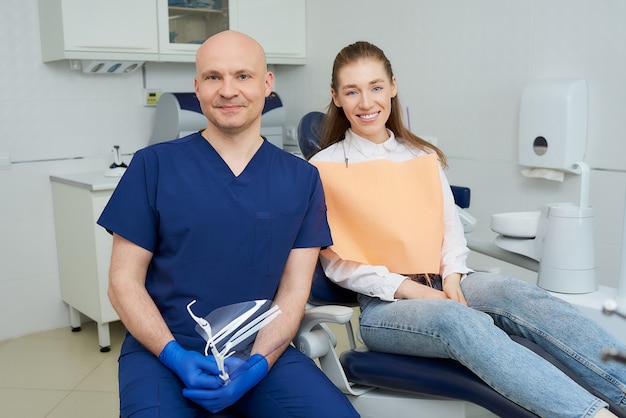 dentista in uniforme e guanti monouso con un paziente in uno studio dentistico