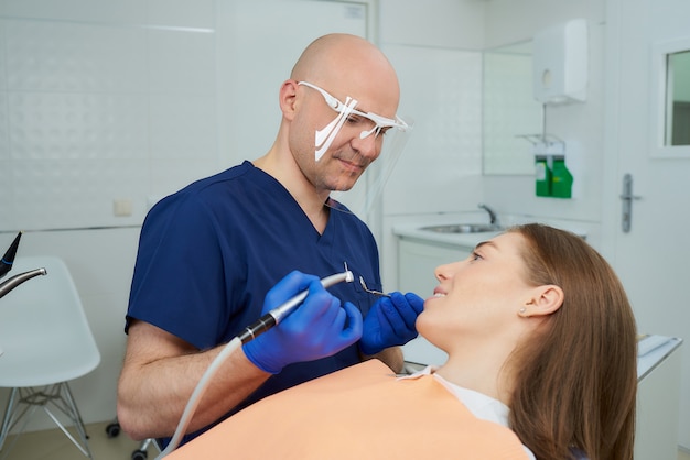 dentista in uniforme e guanti monouso con un paziente in uno studio dentistico