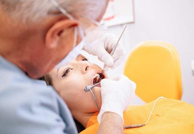 Dentista maschio che cura i denti della donna