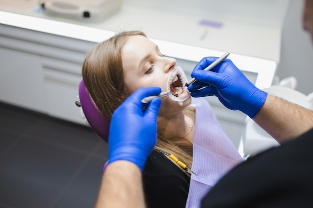 Dentista maschio che esamina i denti del paziente femminile prima del trattamento
