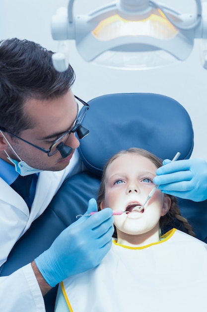 Dentista maschio che esamina i denti delle ragazze