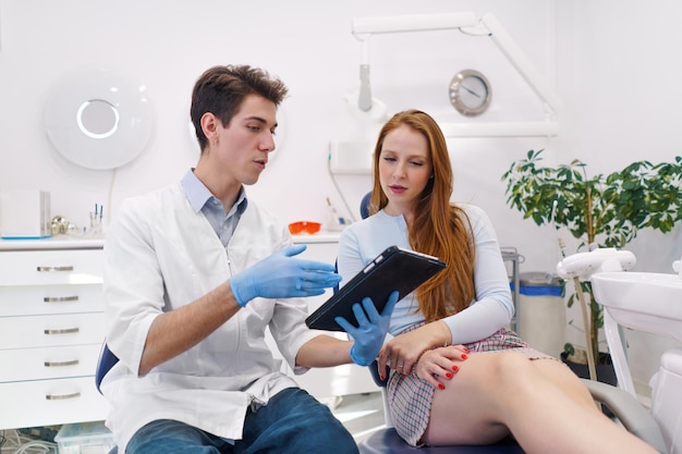 Dentista maschio che mostra la compressa al paziente femminile