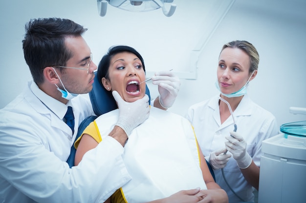 Dentista maschio con l&#39;assistente che esamina i denti dei womans