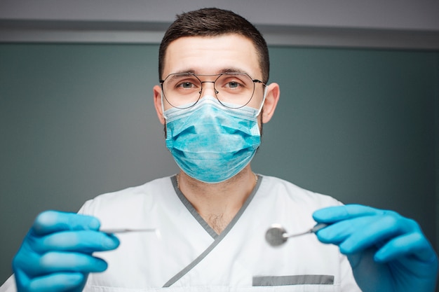 Dentista maschio serio che indossa uniforme e maschera.