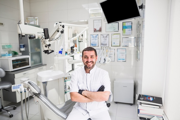 Dentista maschio sorridente in clinica che guarda l&#39;obbiettivo