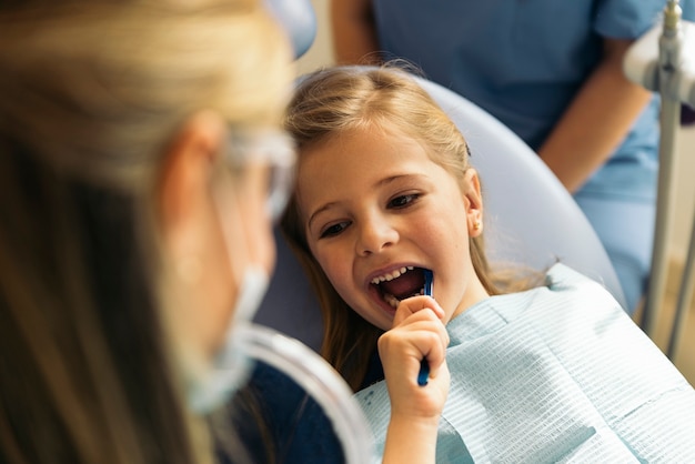 Dentista medico che insegna a un bambino a lavarsi i denti. Concetto medico