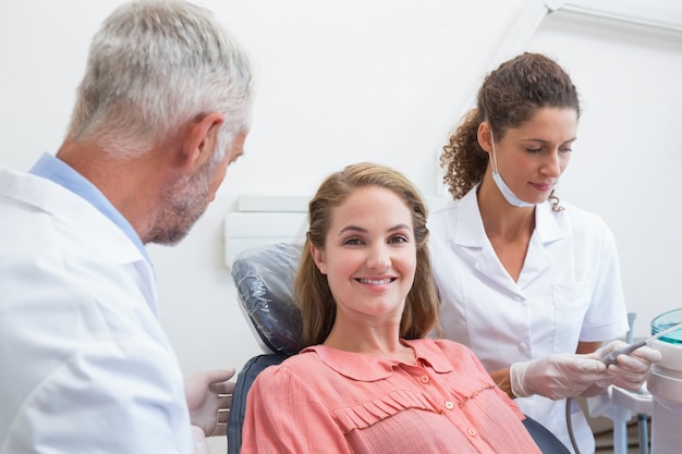 Dentista parlando con paziente mentre infermiera prepara gli strumenti