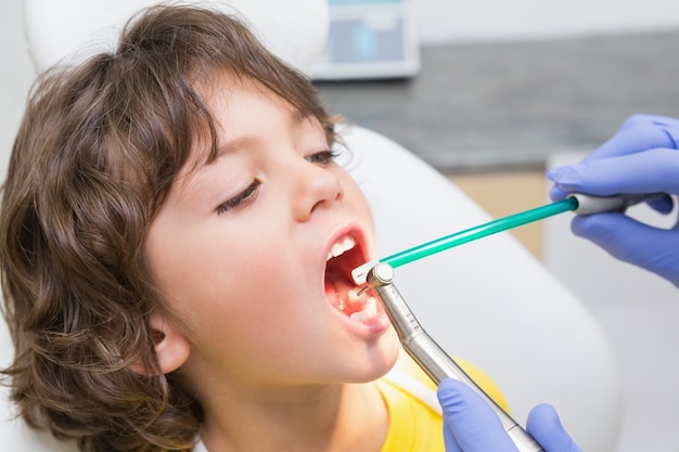 Dentista pediatrico che esamina i denti dei ragazzini nella sedia dei dentisti