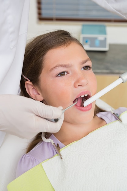 Dentista pediatrico che esamina i denti di una bambina sulla sedia dei dentisti