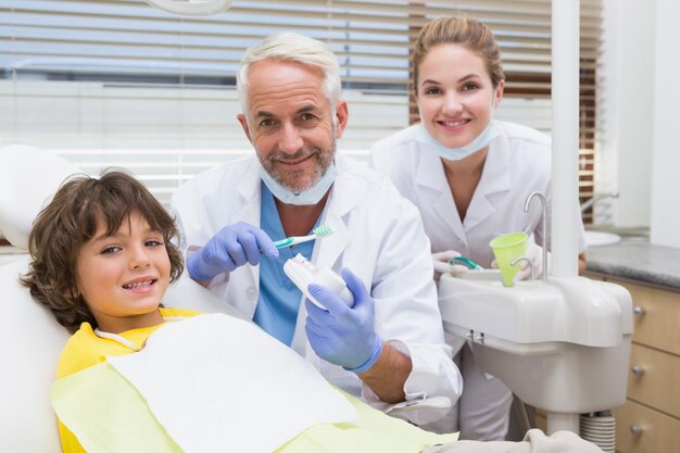 Dentista pediatrico che mostra a ragazzino come lavarsi i denti