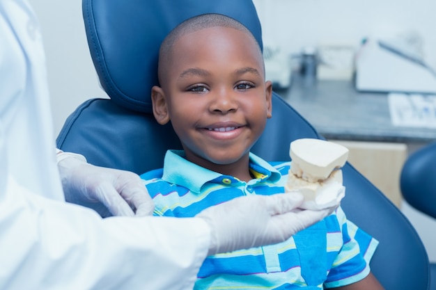 Dentista potato che mostra i denti della protesi del ragazzo