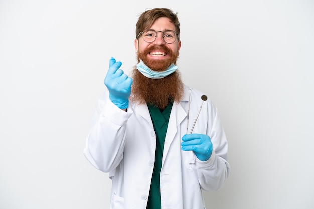 Dentista uomo rossastro che tiene strumenti isolati su sfondo bianco facendo gesto di denaro