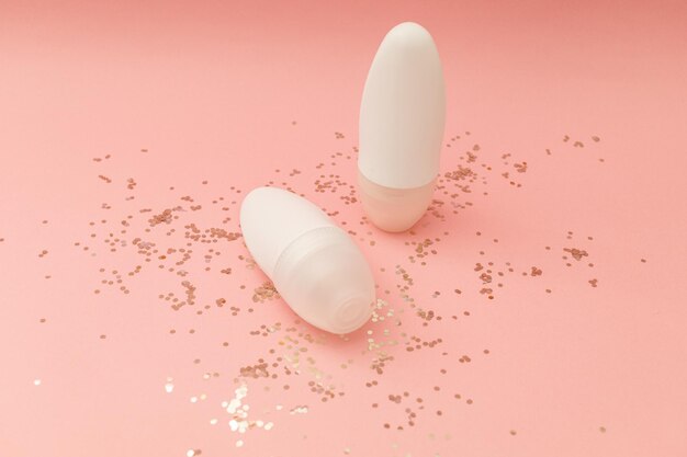 Deodorante a rullo in bottiglia bianca su sfondo rosa