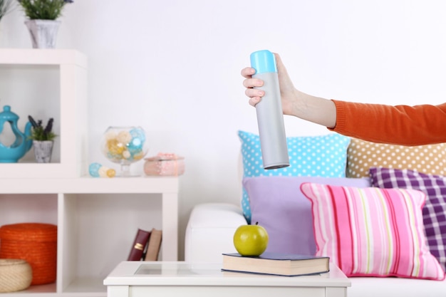 Deodorante per ambienti spruzzato in mano sullo sfondo dell'interno della casa