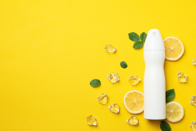 Deodorante spray, ghiaccio e limone su giallo