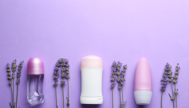 Deodoranti femminili e fiori di lavanda su fondo lilla piatto