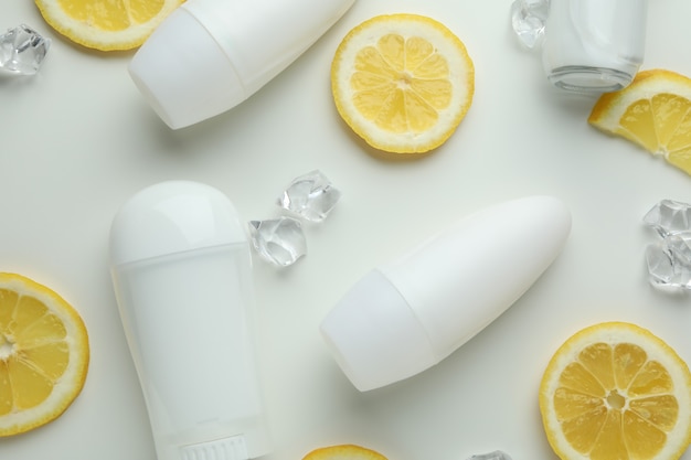 Deodoranti vuoti, fette di limone e cubetti di ghiaccio su sfondo bianco