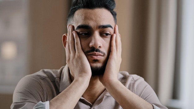 Depresso stanco uomo arabo ispanico ragazzo uomo d'affari lavoratore a casa sentirsi noia depressione massaggiare