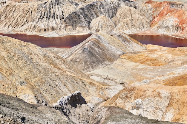 Deserto collinare con un lago rosso in fondo a un burrone sul sito di una vecchia cava di argilla