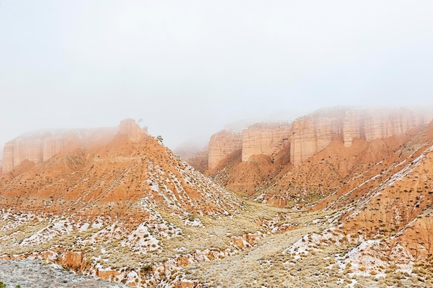 Deserto con montagne marroni parzialmente coperte di neve.