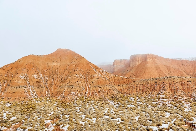 Deserto con montagne marroni parzialmente coperte di neve.