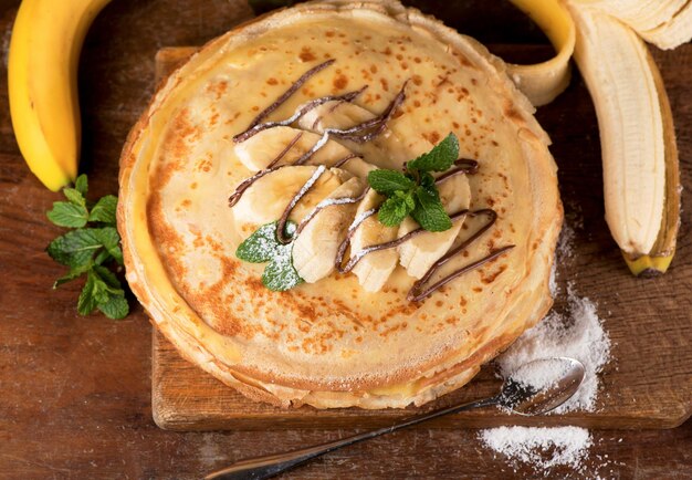 Deserto isolato - pila di pancake con cioccolato da spalmare e banana su un tavolo di legno