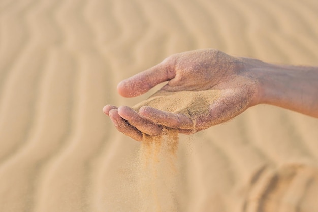 Deserto, la sabbia sbuffa tra le dita della mano di un uomo