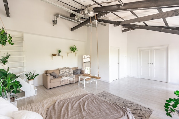 Design della camera da letto di lusso in un cottage rustico in stile minimalista. pareti bianche, finestre panoramiche, elementi decorativi in legno sul soffitto, altalene di corda nel mezzo di una stanza spaziosa.