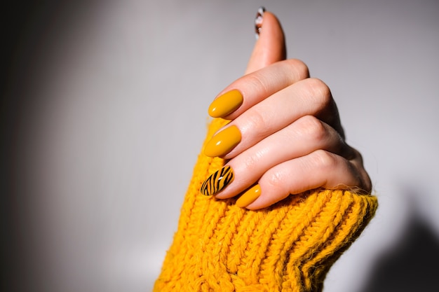 Design delle unghie. Mani Con Il Manicure Giallo Brillante Sullo Sfondo. Primo Piano Di Mani Femminili. Nail art. Manicure della tigre