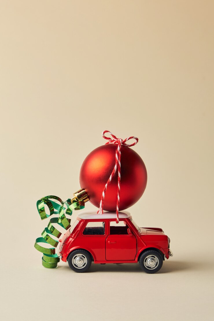 Design minimale per festeggiare il biglietto di auguri di Natale o Capodanno. Consegna di decorazioni e regali. Macchinina rossa e palla di Natale rossa su sfondo chiaro