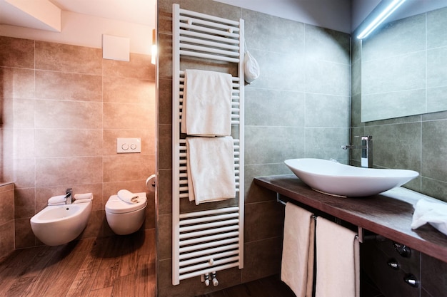 Design moderno del bagno bianco e interni di lusso della casa in una camera d'albergo. Lavandino, specchio, doccia e piastrelle pulite sullo sfondo. Nuovi mobili da toilette con decorazioni di alto livello. Bellissimo stile di ceramica