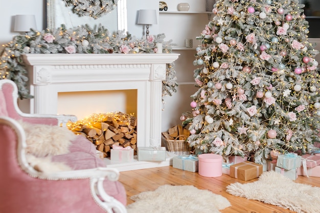 Design moderno della camera con camino in colori chiari decorata con albero di Natale ed elementi decorativi, decorazioni di Capodanno, Buone vacanze invernali, albero di Natale e regali.