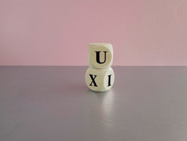 Design UX o design dell'interfaccia utente Trasformato il cubo e cambiato le parole "UX" in "UI" Bellissimo sfondo rosa Concetto aziendale Copia spazio