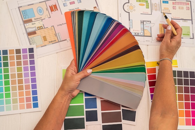 Designer che lavora con la tavolozza dei colori e lo schizzo del piano della casa