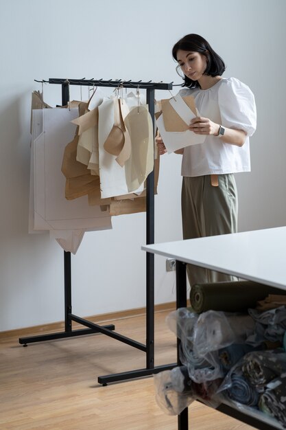 Designer di moda tenere modelli di carta in studio sarta giovane donna o proprietario di atelier in officina