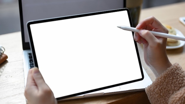 Designer femminile che disegna sull'immagine del primo piano del mockup dello schermo bianco del touchpad del tablet