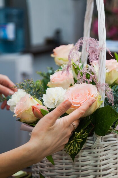 Designer fioraio femminile raccogliendo fiori per fare un bouquet nel cesto bianco. Negozio di fiori che prepara regali per vacanze o decorazioni. Concetto di consegna dei fiori.