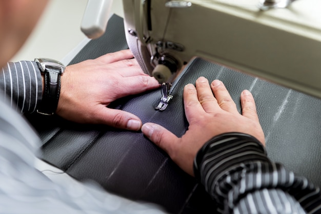 Designer su misura cucire coprisedili. L'uomo usa la macchina da cucire per il suo lavoro. Panno di lavorazione sartoriale. Fabbrica tessile.