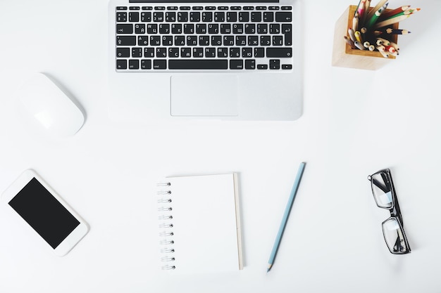 Desktop bianco con smartphone e blocco note