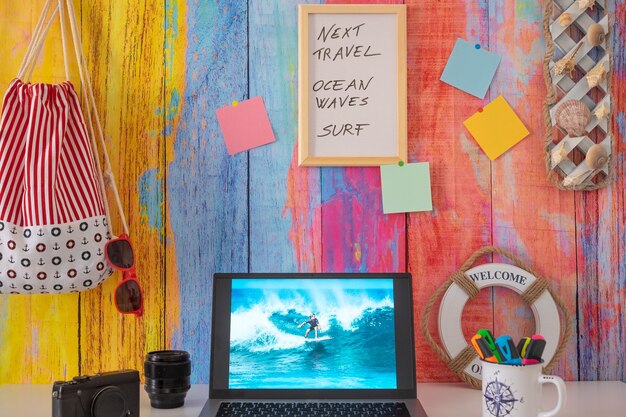 Desktop con computer portatile e fotografia di un giovane surfista. Concetto di vacanze estive e al mare