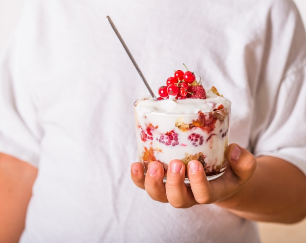 Dessert a strati con panna montata e lamponi in mano d'uomo