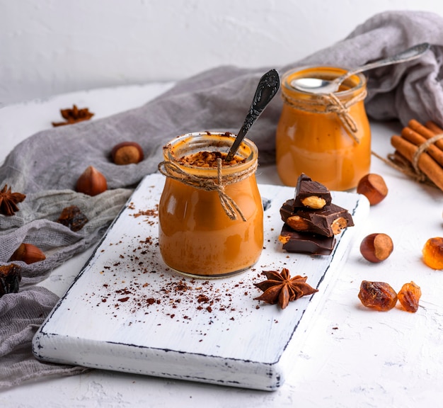 Dessert al caramello Toffee in un barattolo di vetro su una tavola rettangolare bianca