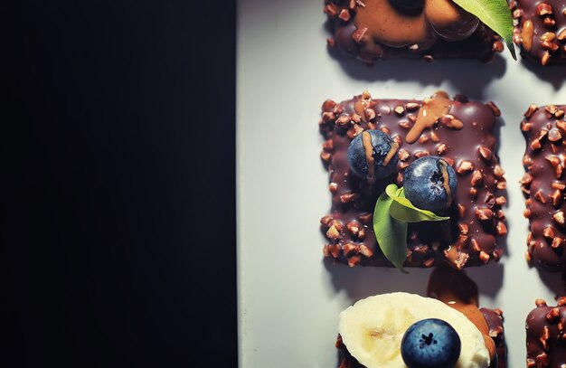 Dessert al cioccolato con noci e frutti di bosco freschi. Snack dolce per biscotti al caffè in glassa e granella di noci con frutta.