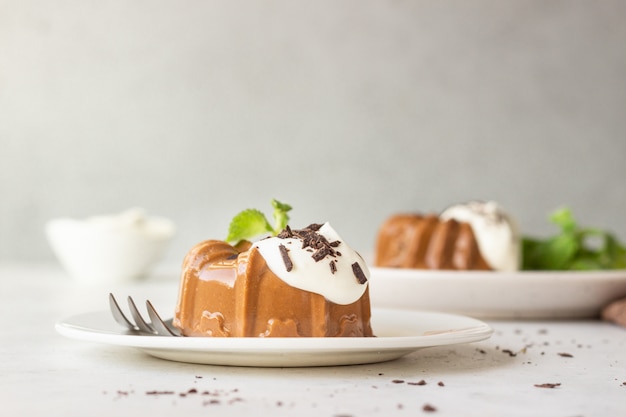 Dessert al cioccolato decorato con panna montata, cioccolato grattugiato e menta. Panna cotta.